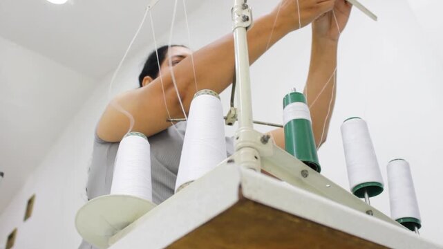 A beautiful Hispanic woman is organizing white thread to work on a sewing machine inside a beauty salon in Neiva, Huila, Colombia. Concept of employment and handmade