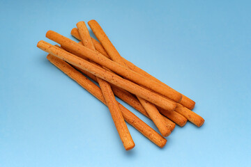 A messy cluster of crispy grissini sticks, often enjoyed as a light appetizer snack, is isolated on a bright blue background. Use in snack advertising.