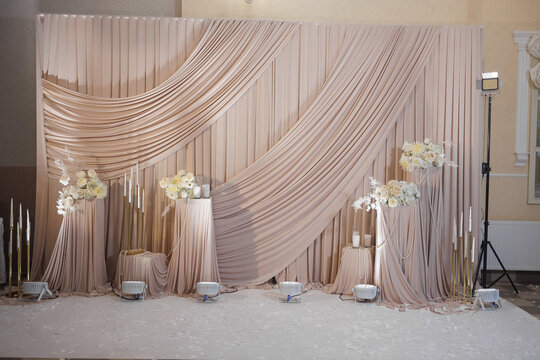 Elegant event backdrop with draped fabric and floral arrangements for special occasions