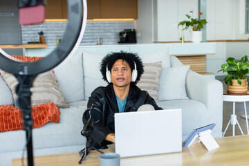 African American man speaking into microphone on floor in modern living room with ring light