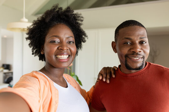 Mid-adult African American couple taking selfie in modern home with smartphone and houseplants - Powered by Adobe