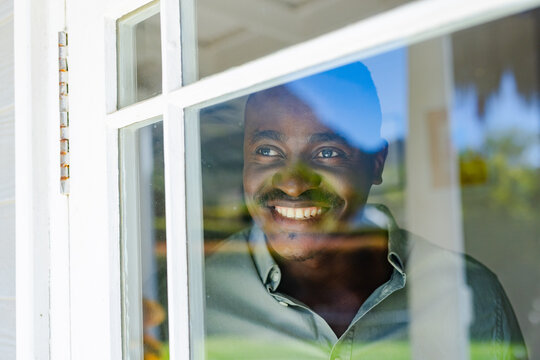 White window frame is casting blue sky and green foliage at home, glass is showing highlights