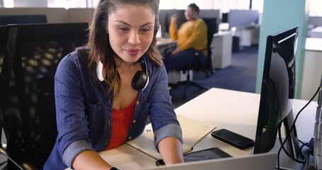 Offscreen cue guiding diverse team in office updating charts on laptop and referencing tablet