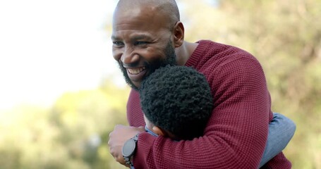 African American father wearing wristwatch hugging son after boy running in sunlit park for reunion