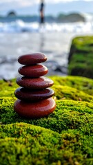 Stacked smooth stones, coastal setting, soft focus beach and person