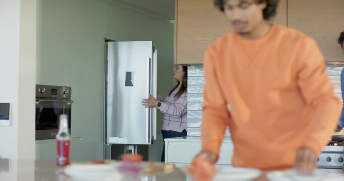 Friends meeting in kitchen slicing tomatoes grabbing cheese stirring and arranging buns for burgers