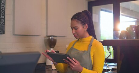 Receiving order alert female barista holding tablet tapping register at counter smiling at customer - Powered by Adobe
