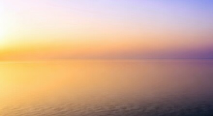 Fototapeta premium A tranquil scene of water reflecting the colors of a sunset sky. The water is smooth and the sky is a gradient of orange, yellow, and purple.