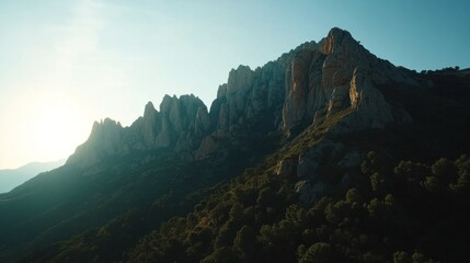 Majestic mountain range with rugged peaks against a clear sky with a warm glow