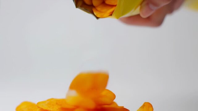 Crispy Potato Chips Falling from a Yellow Bag in Slow Motion on White Background