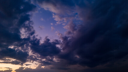 Obraz premium A breathtaking purple and blue sky at dusk with dramatic cloud formations that create a tunnel like effect leading the eye towards the fading light on the horizon after sunset