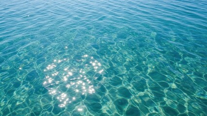 Obraz premium Clear turquoise water surface with sunlight reflections