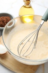 Different ingredients for dough and whisk on table, closeup