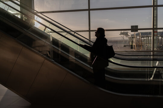 La mujer mayor est&aacute; subiendo por la escalera el&eacute;ctrica del aeropuerto.