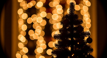 Silhouette of a Christmas tree against a backdrop of warm, glowing bokeh lights, creating a festive and magical holiday atmosphere