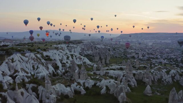 Hot air balloons flying over fairy chimneys rocks at sunrise, Cappadocia, Turkey