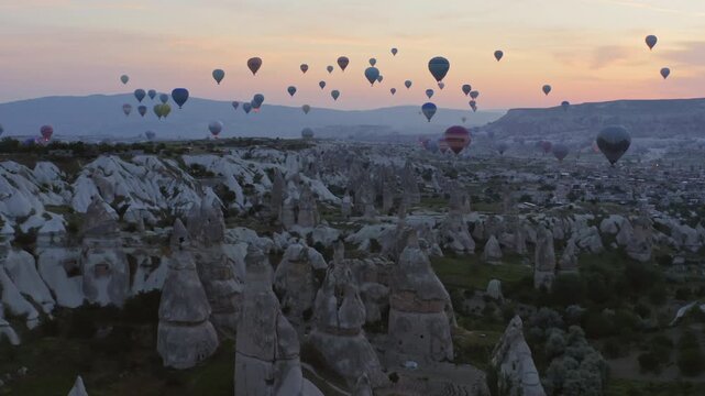 Hot air balloons flying over fairy chimneys rocks at sunrise, Cappadocia, Turkey