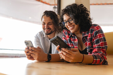 LGBTQ+ friends smiling while using smartphones together