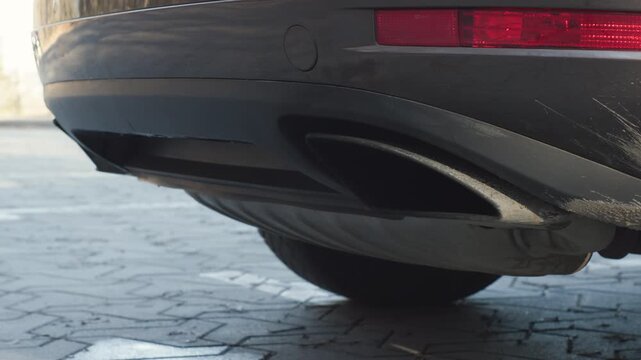 Diesel car exhaust close up as engine stops, deep idle rumble fading out with clean mechanical sound, rear bumper detail outdoors