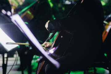 Concert view of contrabass violoncello player with vocalist and musical band during string concert, jazz orchestra performing music, violoncellist cello jazz player on stage in club, music arena hall