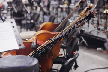 Fototapeta premium Concert view of contrabass violoncello player with vocalist and musical band during string concert, jazz orchestra performing music, violoncellist cello jazz player on stage in club, music arena hall