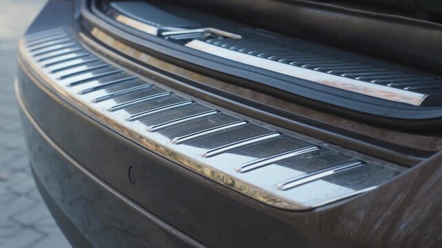 Car trunk door automatic opening with premium chrome bumper sill detail and clean original sound, close up rear view outdoors