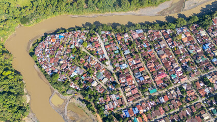 Aerial view of a rural village in Davao City situated along a winding river, showing residential houses, vegetation, and natural waterways captured from above in daylight conditions.