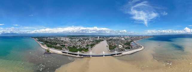 Aerial view of Davao Bancasa Bridge spanning the coastline, showing urban shoreline, water currents, and surrounding cityscape under clear sky conditions.