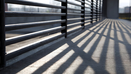 Repeating railing slats creating thin parallel shadows forming clean minimal urban linear repetition