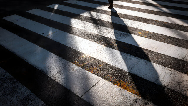 Repeating crosswalk lines enhanced by strong sun creating high-contrast minimal rhythmic ground pattern