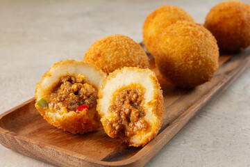 A view of beef and potato balls, on a wooden plate.