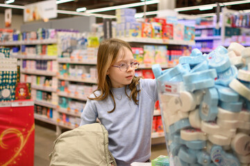 A girl chooses socks or pajamas with a Christmas print. Holiday shopping concept. Christmas gifts.