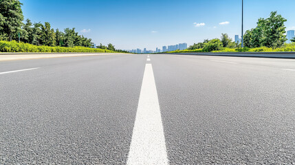 Fototapeta premium Empty asphalt highway centerline leading to distant city skyline under blue sky