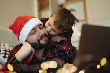 man wearing santa hat with his little cute son buying presents online