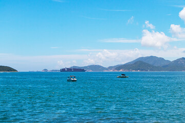 Landscape island paradise green trees in middle of sea with white sky is background. Calm ocean waves yacht floated along with the gentle waves. Suitable for summer vacation travel at Hong Kong.