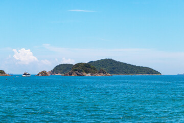 Landscape island paradise green trees in middle of sea with white sky is background. Calm ocean waves and light sunlight in evening were beautiful. Suitable for summer vacation travel at Hong Kong.
