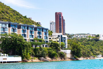 Skyscraper building, Hotel, shopping mall, Villa, seaside on mountains and beach with green trees and blue sky, white clouds and bright sunlight as background. Landscape of Hong Kong's resort.