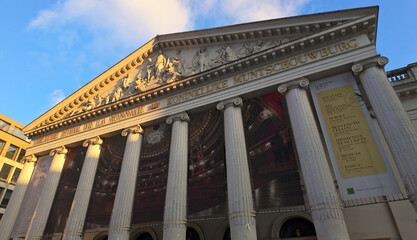 Naklejka premium BRUSSELS, BELGIUM - NOVEMBER 26, 2025 - La Monnaie, De Munt opera house building showcasing neoclassical architecture and current program banners