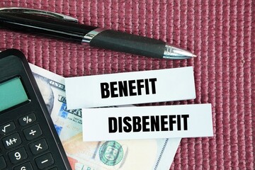 Paper money, pen and paper with the words benefit and disbenefit. Benefits are the positive aspects or advantages of something, while disadvantages are the negative aspects or drawbacks.