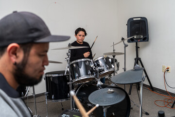 Young drum student watching the instructor closely as they play together at the drum kit. Private drum lesson focused on rhythm, percussion skills, and musical learning