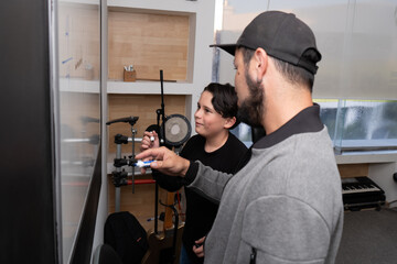 Teacher demonstrates rhythm notation on the board while the student observes closely during a drum and drums session. Music training, solfege guidance, rhythmic development.