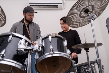 Music teacher playing drums while the student watches with an embarrassed expression after a mistake. Drum learning, rhythm practice, music education, private lesson