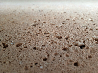 Close-up macro texture of rough porous tan limestone or Marés stone. Natural surface with tiny pits, holes, weathered, absorbent, pitted, sedimentary rock, textural detail, abstract background. 