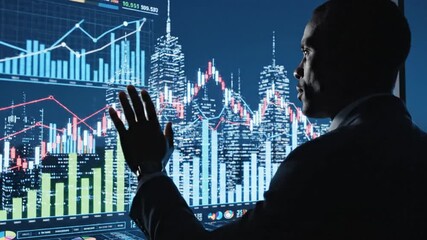 A man analyzes financial charts on a screen displaying data overlaid over a city skyline at night - Powered by Adobe