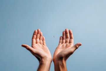 Hands cupped toward a tiny bird soaring in a vast, clear blue sky