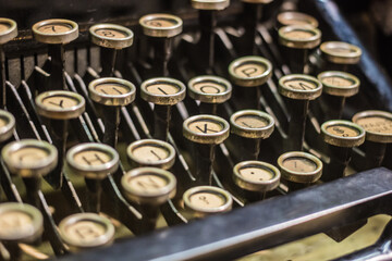 A close-up of an antique typewriter with round keys and visible metal levers, showing vintage writing technology.