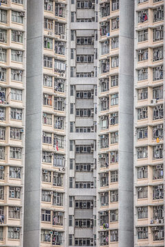 A high-rise building with repetitive balconies, laundry, and air conditioning units, showing utilitarian urban living in a dense city.
