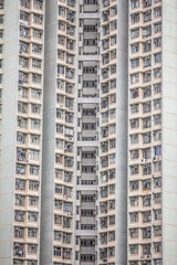Fototapeta premium A high-rise residential building with repetitive balconies, laundry, and air conditioning units, emphasizing vertical urban density.