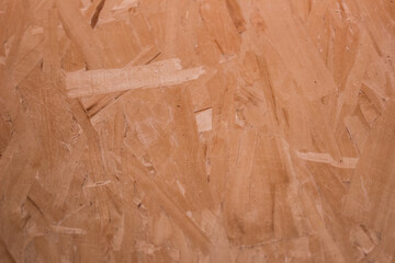 A close-up of oriented strand board showing overlapping wood flakes, used in construction for its strength and affordability.