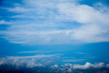 A vibrant sky with wispy cirrus clouds above and darker cumulus clouds below, creating a dynamic atmospheric scene.